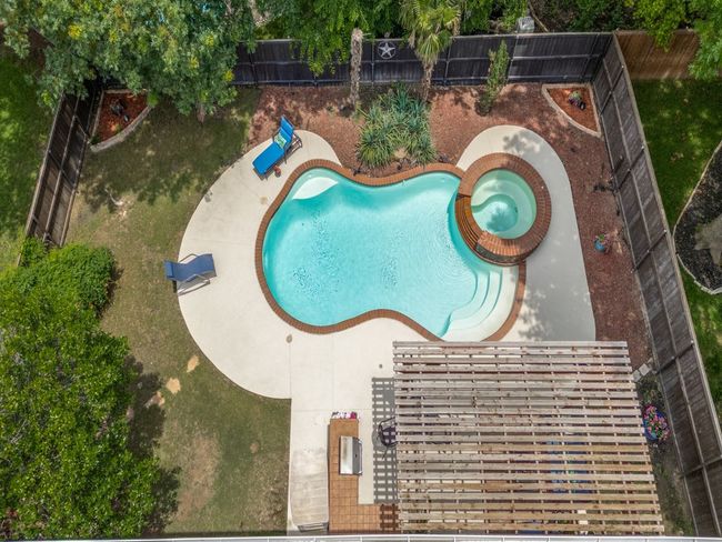 View of swimming pool featuring a fenced backyard lush landscaping. | Image 27