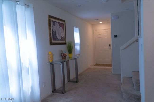 Hall with light carpet, visible vents, and baseboards | Image 11