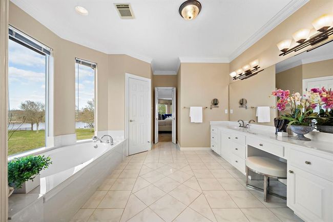 he primary bathroom is a serene retreat that boasts large windows offering a sweeping view of the picturesque estate. These windows not only flood the space with natural light but also provide a soothing panorama that enhances the room's calming atmosphere. | Image 24