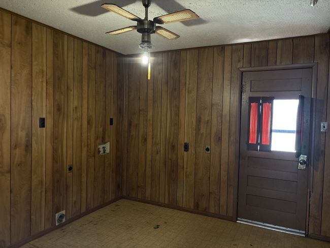 Spare room featuring a textured ceiling, wood walls, and ceiling fan | Image 15