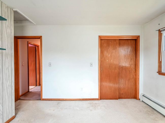 Unfurnished bedroom featuring light colored carpet and a baseboard heating unit | Image 25
