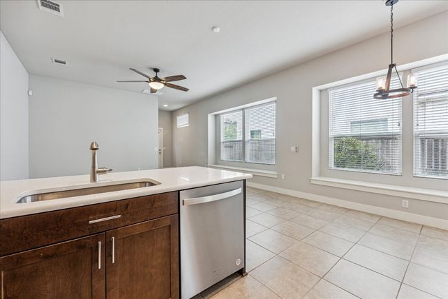 Kitchen featuring dishwasher, a sink, hanging light fixtures, light tile patterned floors, and light countertops | Image 13