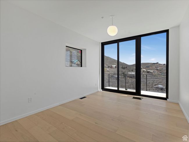 Empty room with visible vents, baseboards, light wood finished floors, and floor to ceiling windows | Image 28