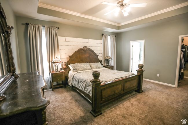 Bedroom featuring crown molding, carpet, a raised ceiling, a spacious closet, and baseboards | Image 23