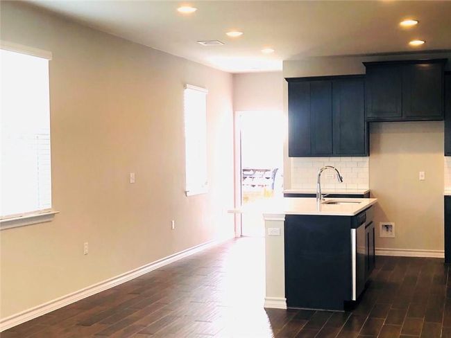 Kitchen with dark wood-type flooring, backsplash, light countertops, recessed lighting, and dark cabinets | Image 7