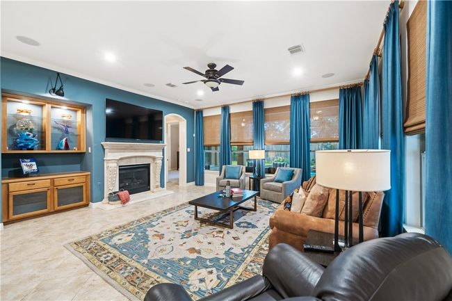 Living room with a ceiling fan, a premium fireplace, ornamental molding, arched walkways, and recessed lighting | Image 4