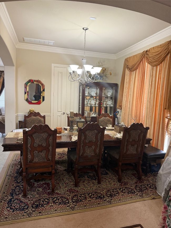 Carpeted dining room featuring a chandelier, arched walkways, and ornamental molding | Image 7