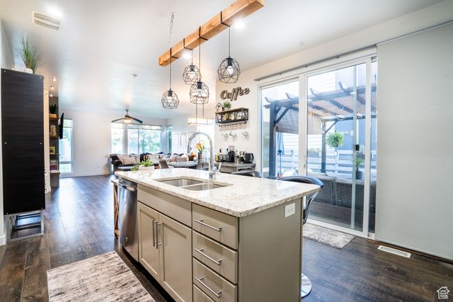 Kitchen with dishwasher, gray cabinets, open floor plan, dark wood-style floors, and light stone counters | Image 6
