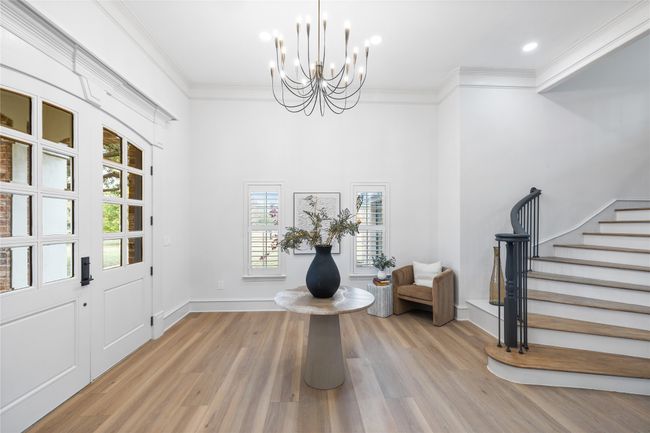 Foyer entrance featuring a chandelier, wood finished floors, stairway, and crown molding | Image 6