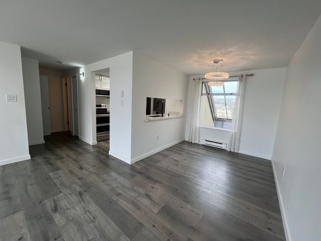 Unfurnished living room featuring a baseboard radiator, a chandelier, and dark wood-type flooring | Image 10