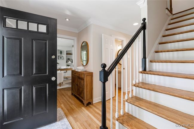 Foyer featuring hardwood flooring, ornamental molding, and recessed lighting. Off to the left is a partial view of the living room/office with double doors. Coat closet and powder room are also off the foyer. | Image 5
