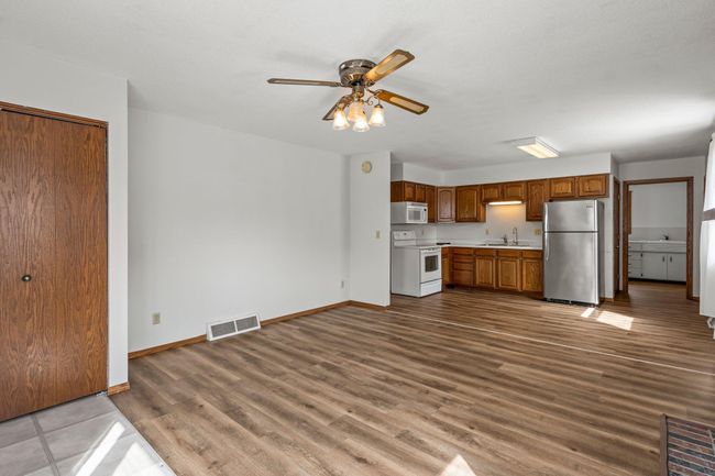 An alternative perspective of the living room highlights the open-concept design, with a clear view of the kitchen and the hallway leading to the laundry room. | Image 5