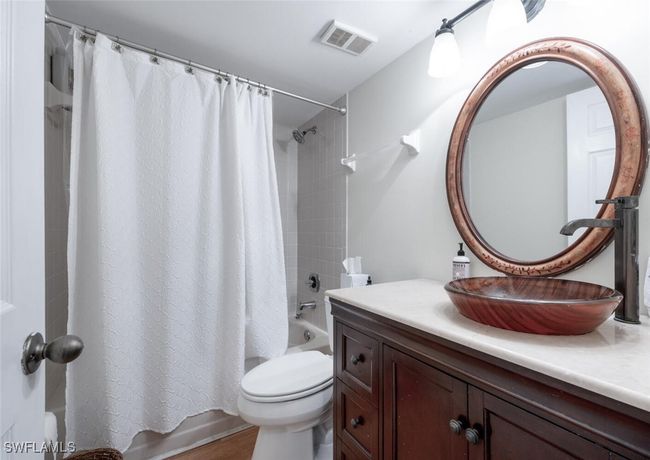 Bathroom featuring shower / bath combination with curtain, toilet, vanity, and visible vents | Image 15