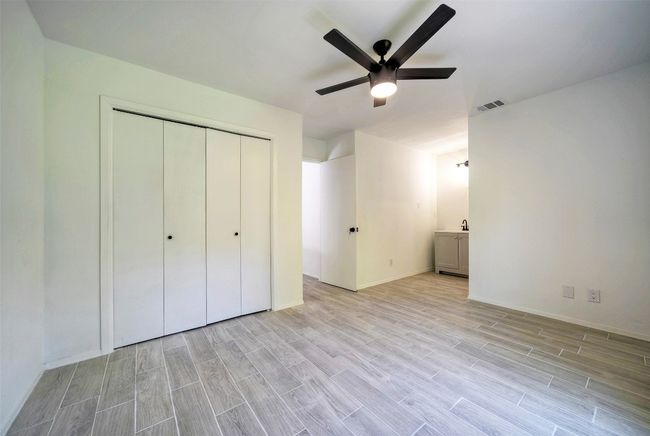 Unfurnished bedroom featuring light wood-style flooring, a closet, ceiling fan, and ensuite bath | Image 12