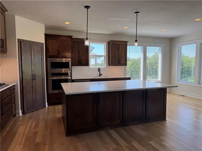 Kitchen with appliances with stainless steel finishes, light wood-style flooring, light countertops, a center island, and recessed lighting | Image 4