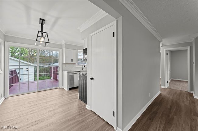 Hall with baseboards, ornamental molding, light wood finished floors, and a sink | Image 13