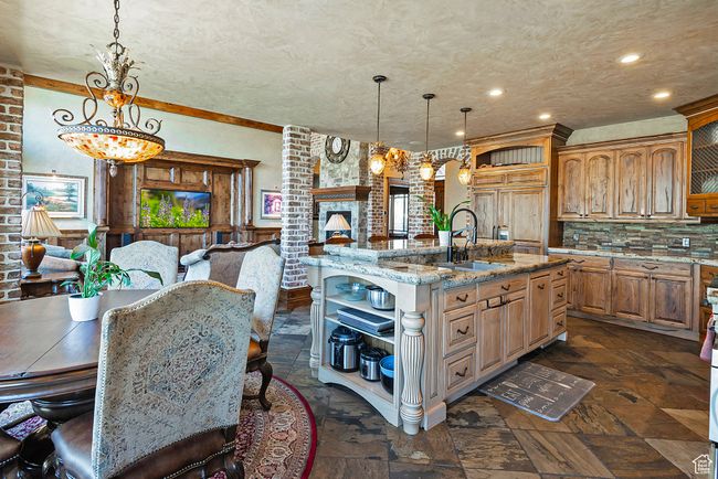 Kitchen with stone finish floor, open shelves, light stone counters, a sink, and decorative backsplash | Image 25