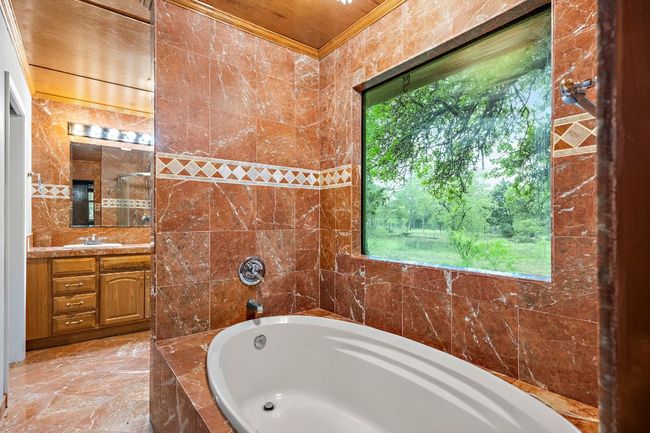 Full bath featuring a tub to relax in, a wealth of natural light, and double vanity | Image 19