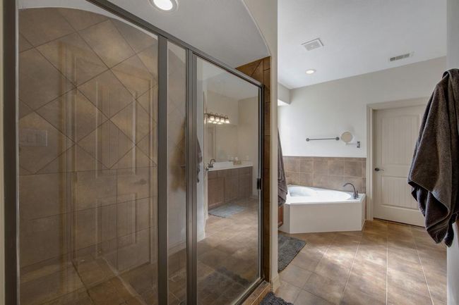Large tiled shower with bench seat, tile flooring, relaxing jetted tub, canister lights | Image 24