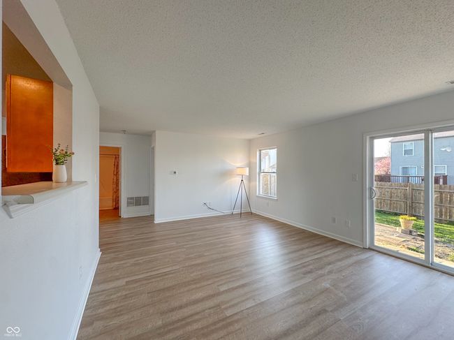 unfurnished living room with visible vents, baseboards, light wood finished floors, and a textured ceiling | Image 20