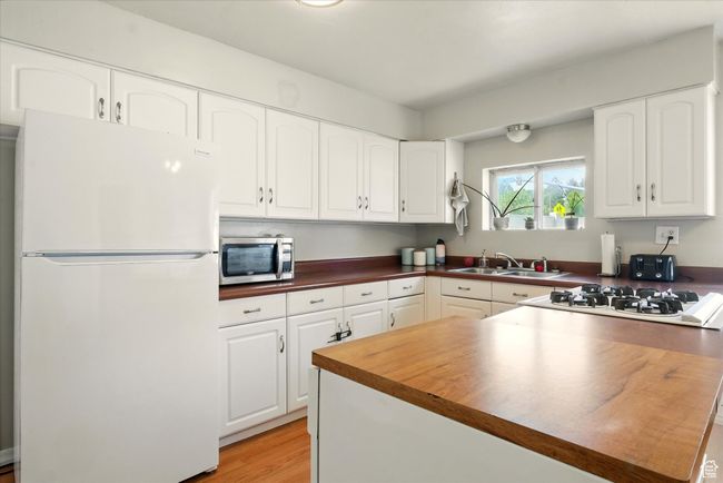 Kitchen with white appliances, white cabinetry, light wood-style flooring, and butcher block counters | Image 5