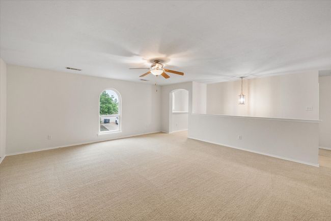 Empty room featuring ceiling fan, light colored carpet, and arched walkways | Image 21