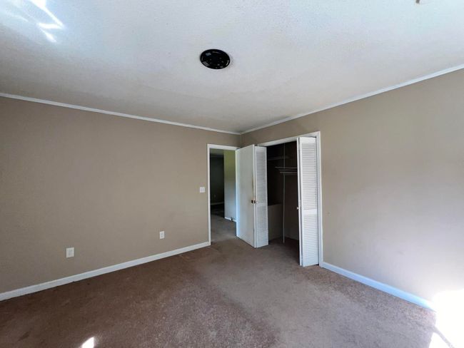 Unfurnished bedroom with carpet flooring, crown molding, baseboards, and a closet | Image 12