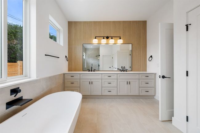 Bathroom with a stall shower, double vanity, a freestanding tub, and tile patterned flooring | Image 18