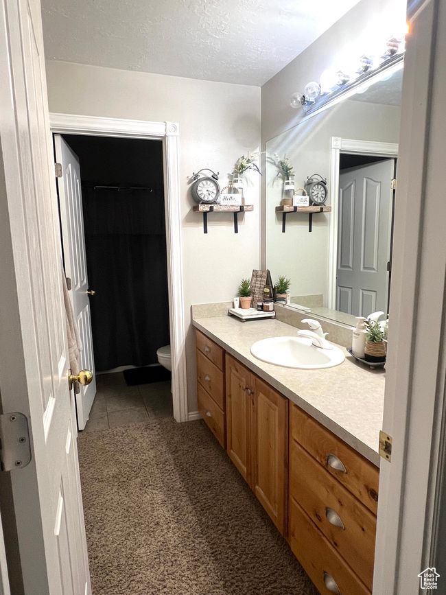 Bathroom with toilet, vanity, tile patterned flooring, and a textured ceiling | Image 11