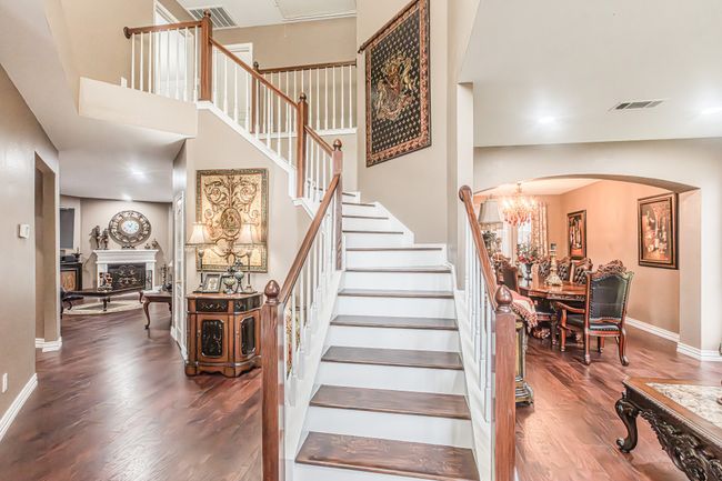 Stairs featuring arched walkways, wood finished floors, a chandelier, a fireplace, and a high ceiling | Image 18