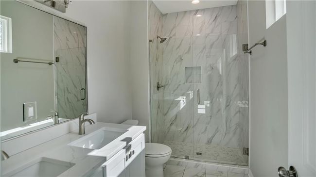 Bathroom featuring marble finish flooring, a marble finish shower, toilet, vanity, and recessed lighting | Image 17