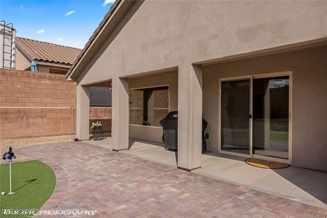 View of patio with an area to practice putting, fence, and area for grilling | Image 50