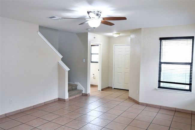Spare room featuring light tile patterned floors, visible vents, a ceiling fan, baseboards, and stairs | Image 5