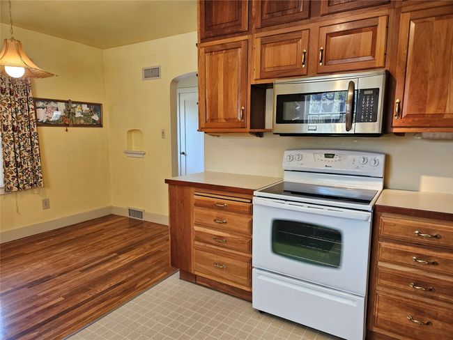 Kitchen featuring stainless steel microwave, white range with electric cooktop, visible vents, and arched walkways | Image 11