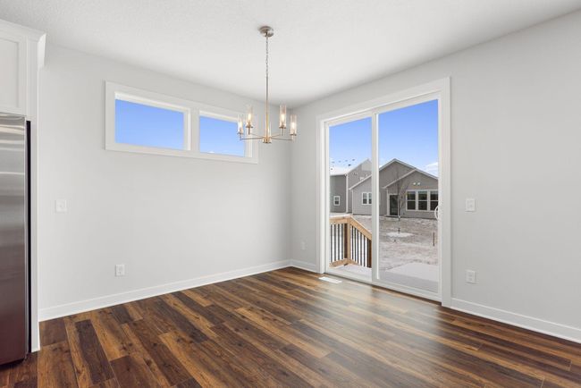 Soaked in natural sunlight from the 8 ft. patio door and added dining windows, the home's eat-in dining room offers plenty of space for a dining table, perfectly situated at the heart of the home. | Image 13