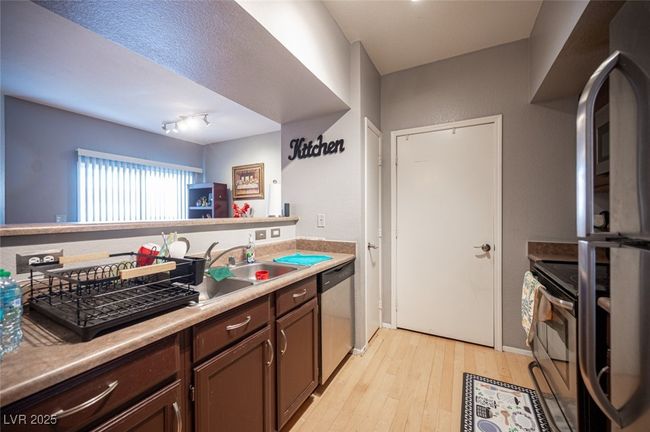 Kitchen featuring dark brown cabinetry, appliances with stainless steel finishes, a sink, light countertops, and light wood finished floors | Image 15