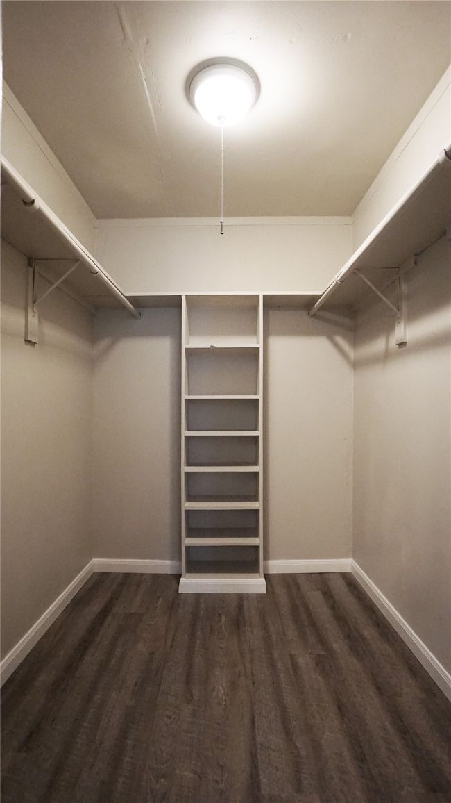 The primary bedroom has a good-sized walk-in closet with shelving and vinyl plank flooring | Image 14