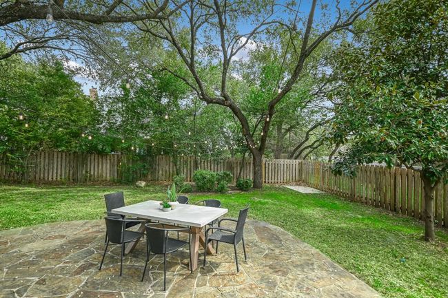 View of patio with outdoor dining space and a fenced backyard. | Image 32