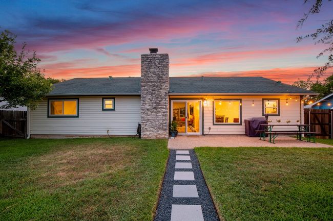 Rear view of house featuring a patio, a chimney, and a shingled roof | Image 23