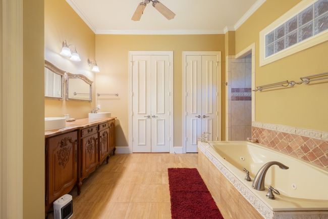 Bathroom with a sink, double vanity, a ceiling fan, a whirlpool tub, and crown molding | Image 18