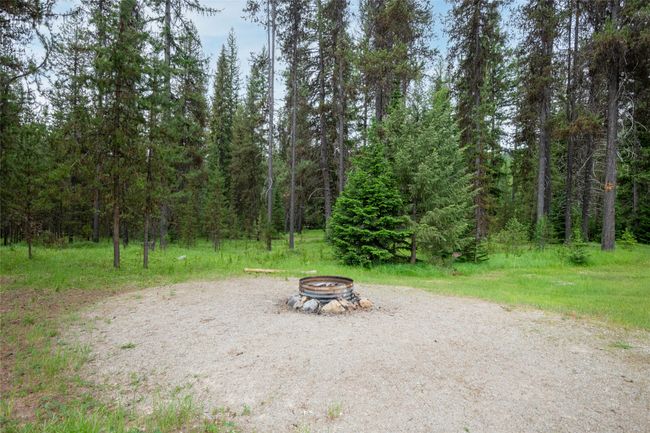View of yard with a fire pit and a view of trees | Image 30
