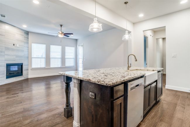 Kitchen featuring stainless steel dishwasher, open floor plan, dark brown cabinets, a ceiling fan, and light stone counters | Image 8