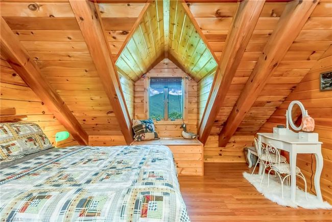 The upper-level bedroom in the log cabin offers captivating mountain views, while a mirrored second bedroom on the opposite side of the loft provides additional space and comfort, combining serene natural surroundings with cozy accommodation. | Image 36