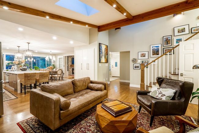Living room featuring beam ceiling, a chandelier, stairs, light wood finished floors, and recessed lighting | Image 6