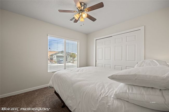 Bedroom with baseboards, dark carpet, a closet, and a ceiling fan | Image 14