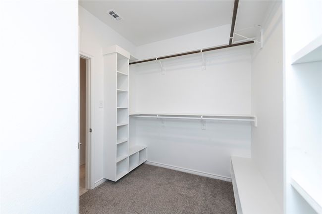 Walk in closet featuring dark colored carpet | Image 19