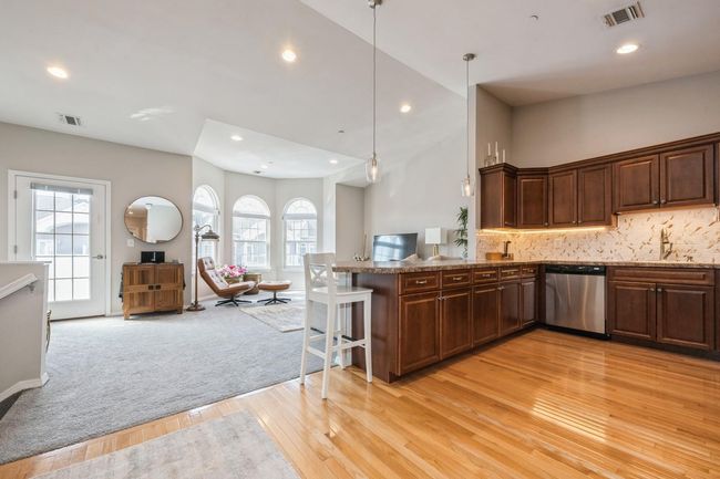 Kitchen featuring stainless steel dishwasher, open floor plan, visible vents, and light wood-style flooring | Image 6