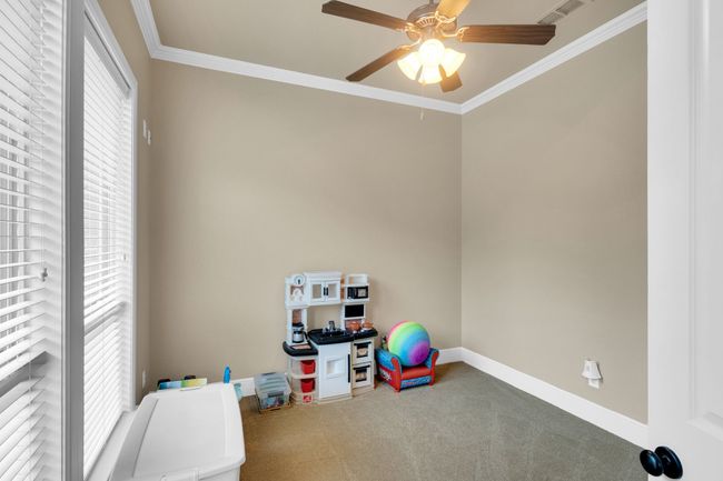 sitting or exercise room featuring carpet flooring, a ceiling fan, and ornamental molding | Image 25