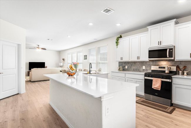 Kitchen featuring visible vents, stainless steel appliances, light countertops, light wood-style floors, and a sink | Image 10