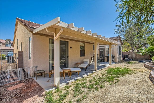 Rear view of house with stucco siding, a fenced backyard, a patio area, and a tile roof | Image 39